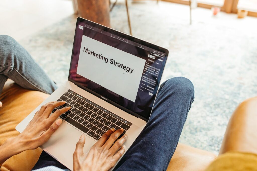 A Arte de Atrair Leitores Close-up of hands using a laptop displaying a marketing strategy presentation indoors.